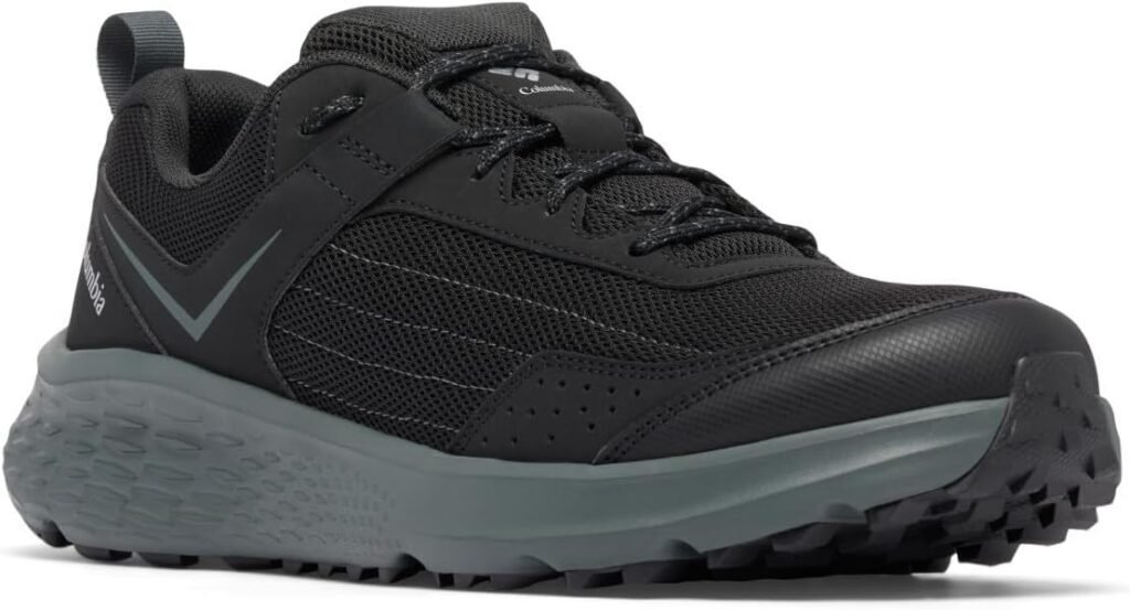 A black Columbia trail running shoe with a white and light green speckled midsole and a durable black outsole, featuring subtle grey accents and reflective laces.