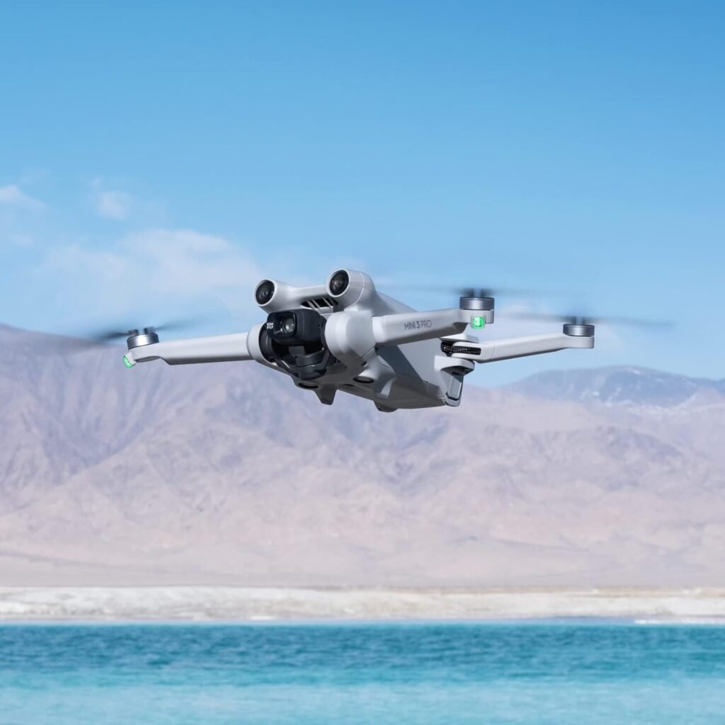 A white DJI Mini 3 Pro drone flying over blue water with mountains in the background, highlighting its use as a Best Drone Camera.