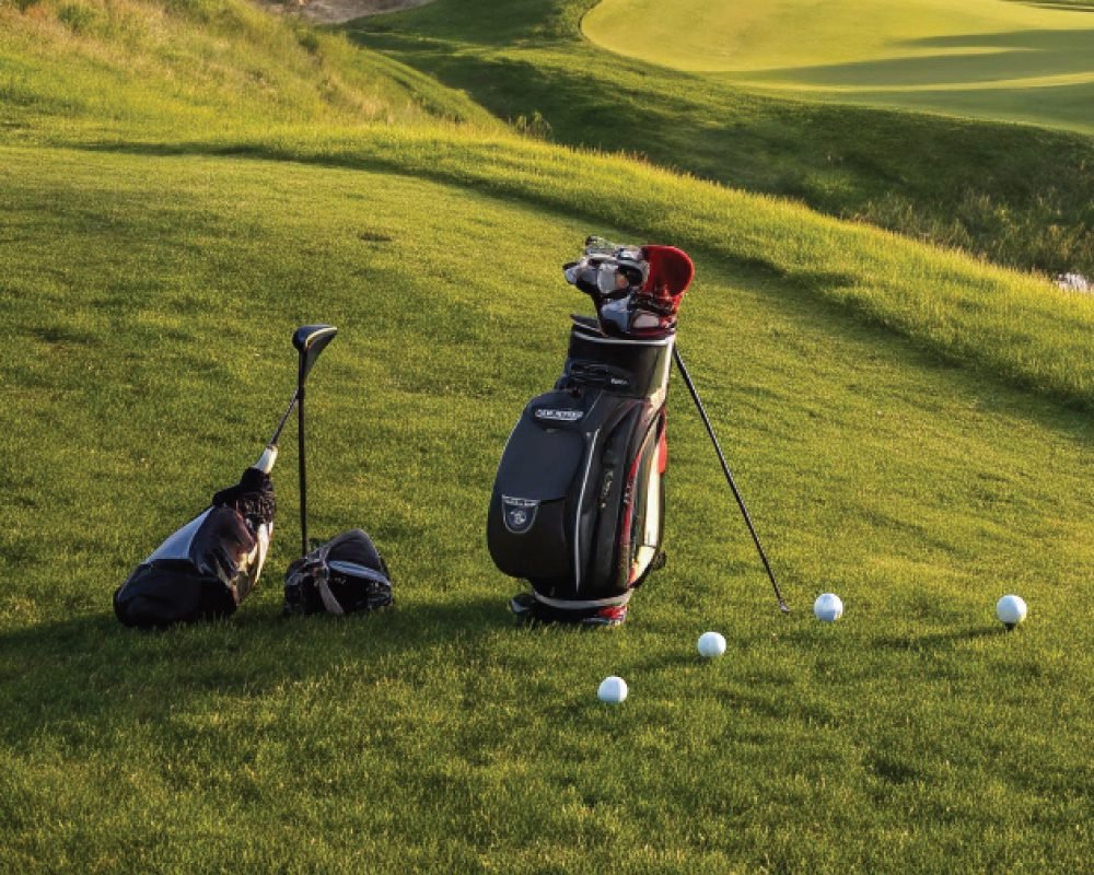 Two golf bags with clubs and several golf balls on a lush green course, representing the perfect day for Golf and Nature.